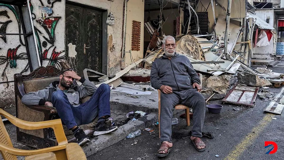 Algunos palestinos esperan a las afueras de las ruinas de lo que era un campo de refugiados, destruido por un bombardeo israel&iacute; esta semana. Foto: AFP.