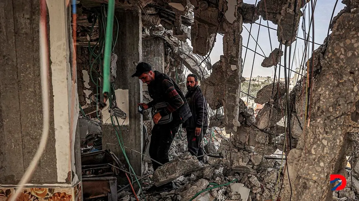 Algunas personas inspeccionan lo que qued&oacute; de un edificio destruido por un bombardeo israel&iacute; en Rafah, al sur de Gaza. Foto: Said Khatib / AFP.