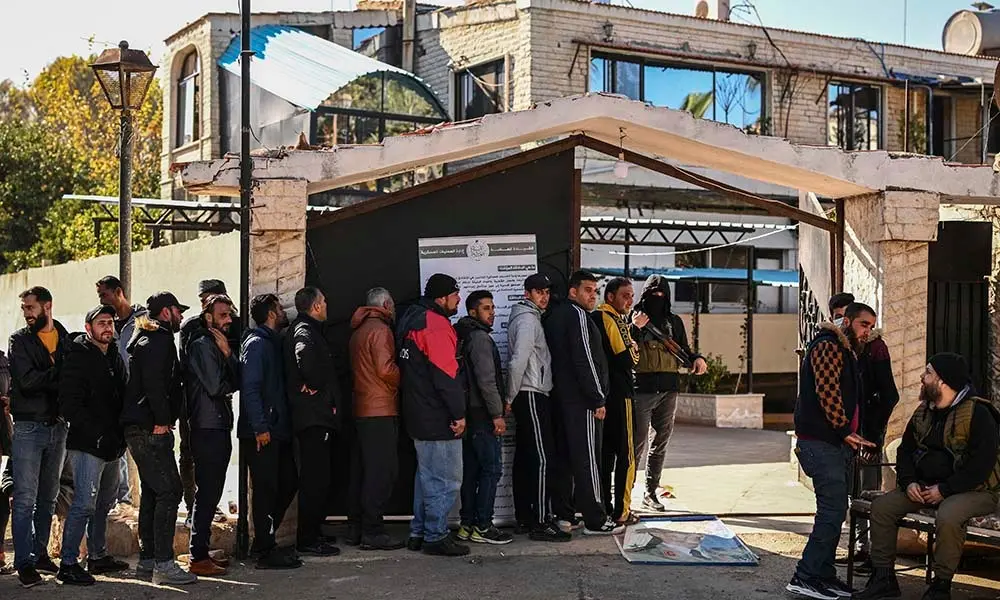 Soldados y polic&iacute;as sirios se aprestan a registrarse un centro creado por las nuevas autoridades para entregar sus armas y normalizar su status. Foto: Aris Messinis / AFP.