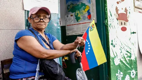 Una mujer ondea la bandera de Venezuela, en medio del refer&eacute;ndum sobre el territorio en disputa con Guyana. Foto: Pedro Rances Mattey / AFP.