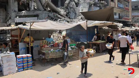 Algunas personas tratan de comprar productos b&aacute;sicos en una poblaci&oacute;n del centro de Gaza, mientras la guerra sigue. Foto: Eyad Baba / AFP.