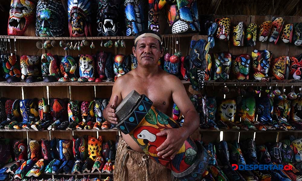 Oscar Quirós, un indígena maleku, posa con artículos tradicionales de su cultura, en un local donde se ofrecen estas piezas a los turistas. Foto: Ezequiel Becerra / AFP.